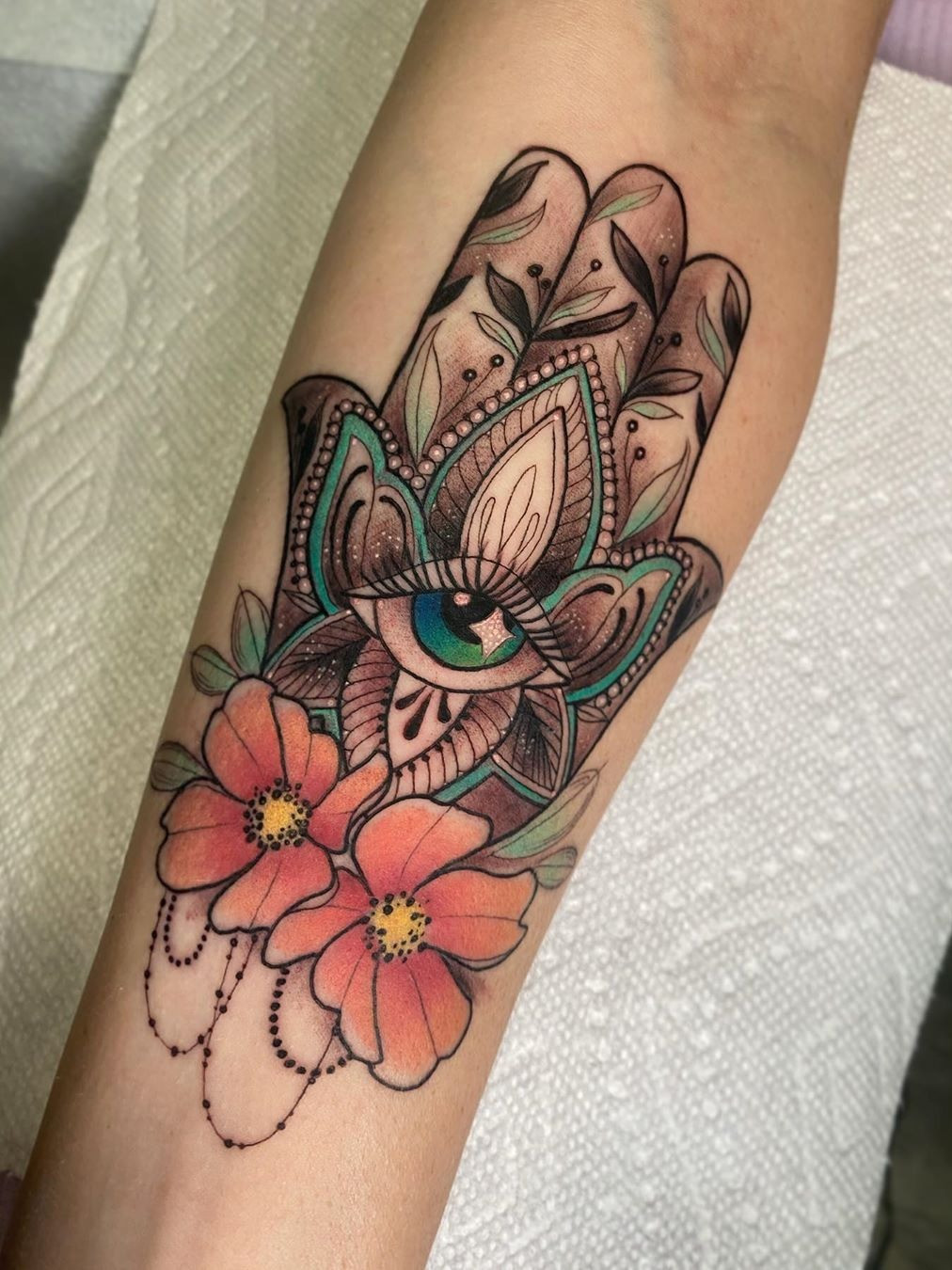 A Hamsa tattoo with detailed floral patterns, combining nature and spirituality in a beautiful design
