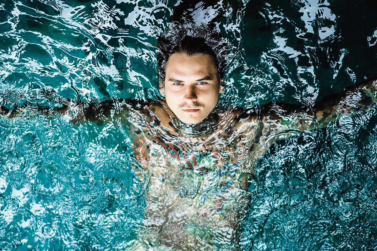 A person swimming in a pool with a tattoo on their arm.