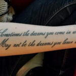 Alt text: A minimalist me myself and i tattoo featuring a delicate lotus flower and the inscription 'Self-love'.