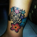 Tattoo of a zebra and flowers on the leg, representing life amidst pain