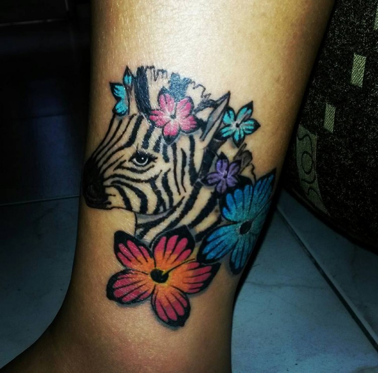 Tattoo of a zebra and flowers on the leg, representing life amidst pain