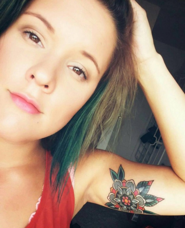 Tattoo of a colorful mandala on the upper arm, symbolizing self-acceptance and peace