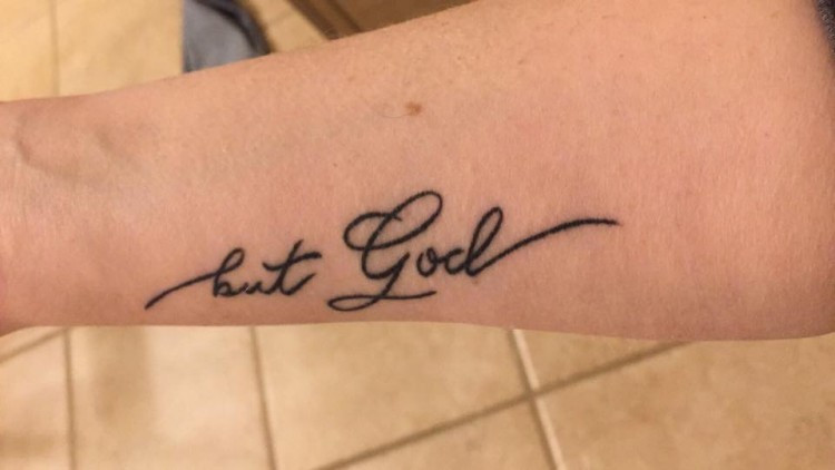 Tattoo on arm with the words &quot;But God,&quot; symbolizing faith and resilience