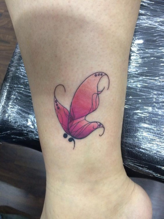 Tattoo on the ankle with a butterfly and semicolon, representing rebirth and continuation of life