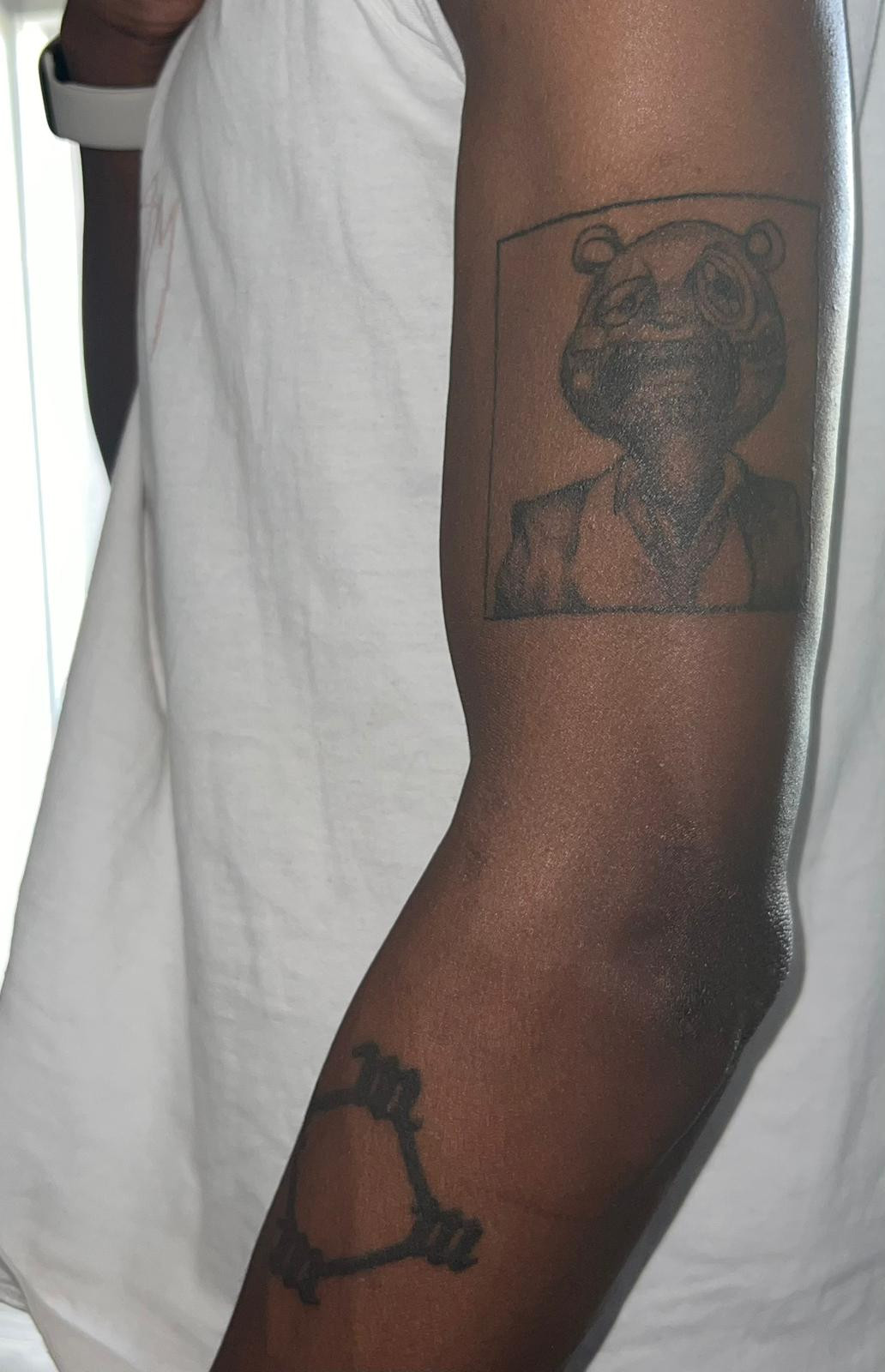 An arm of a Kanye West fan showing My Beautiful Dark Twisted Fantasy tattoo art