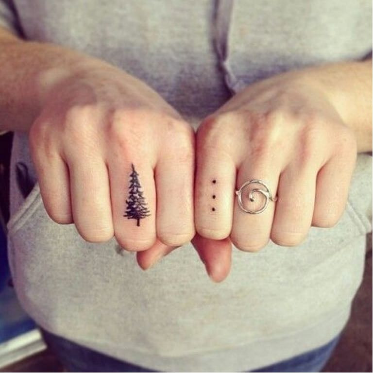 Two simple dot tattoos on fingers, embodying duality and harmony
