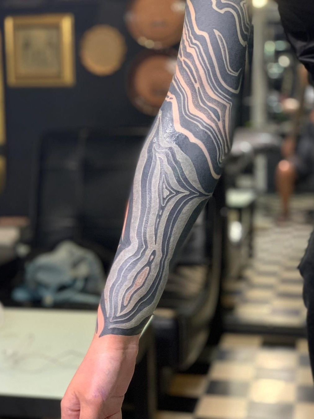 A person undergoing a blackout tattoo session, showcasing the extensive coverage and potential discomfort