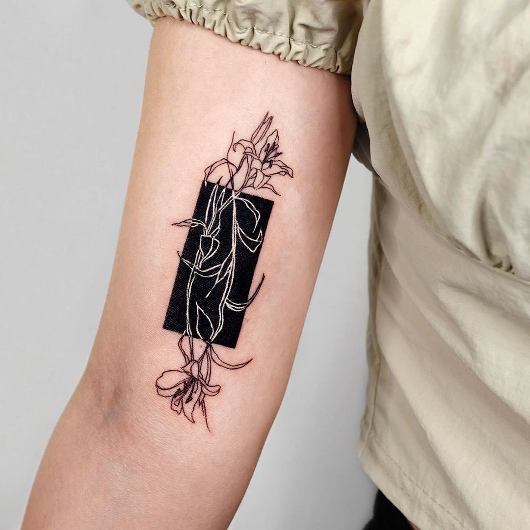 A healed white ink over blackwork tattoo, showing how the design has aged and the need for potential touch-ups