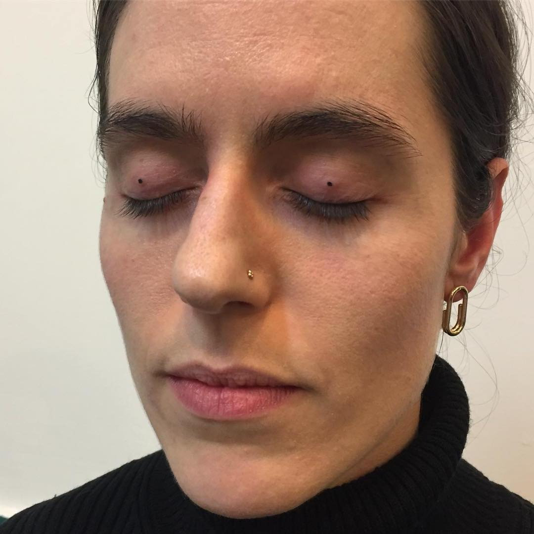 An artist meticulously performing an eyelid tattoo, showcasing the precision and attention to detail required