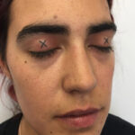 Close-up of an artist tattooing a detailed design on an eyelid, showcasing precision and skill
