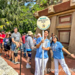 A Disney Cast Member smiles warmly at guests, showcasing acceptable wrist tattoos.