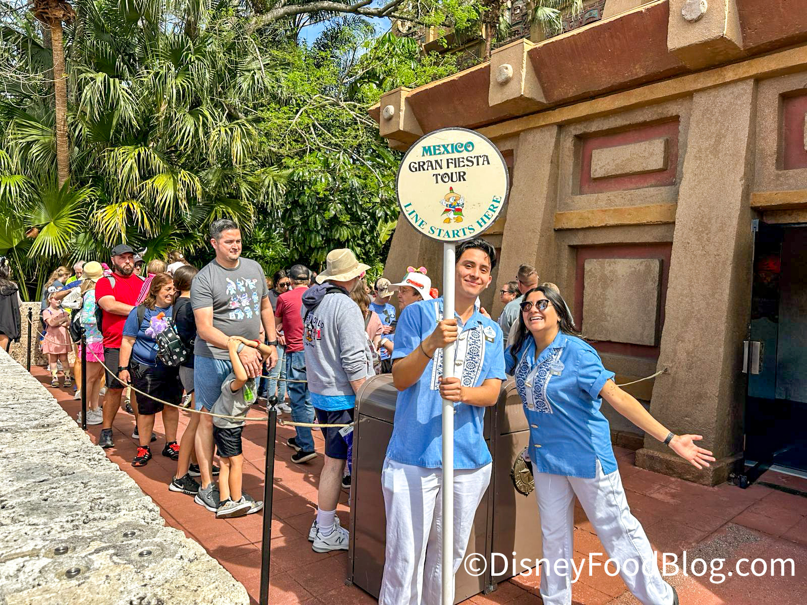 A Disney Cast Member smiles warmly at guests, showcasing acceptable wrist tattoos.