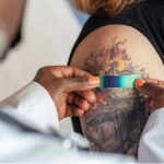 Close-up of a tattoo machine in action, with a focus on the needle and ink, highlighting the precision required for safe tattoo application.