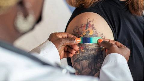 Close-up of a tattoo machine in action, with a focus on the needle and ink, highlighting the precision required for safe tattoo application.