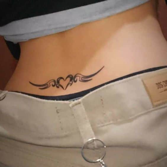 Lower back tattoo with tribal heart design above waistband.
