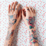 Hand applying sunscreen to a colorful arm tattoo