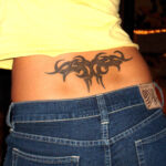Lower back tattoo, alt text: A detailed lower back tattoo featuring intricate floral patterns, symbolizing the popularity of this placement in the 1990s and early 2000s.