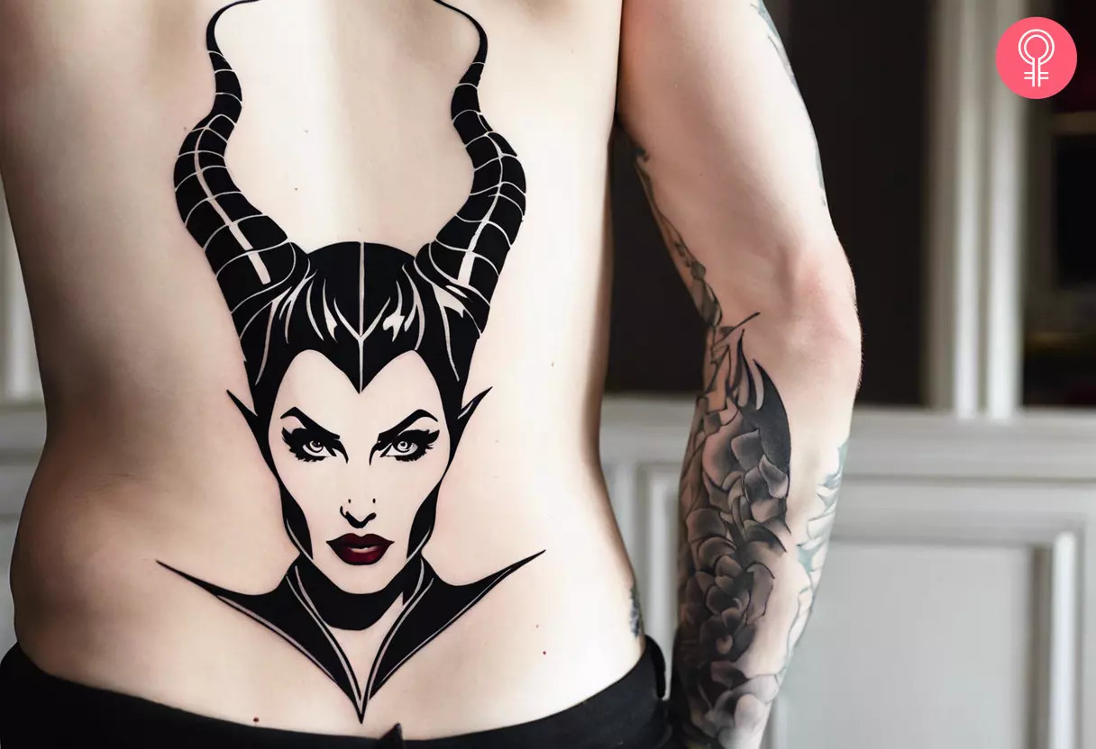A man showcasing a Maleficent outline tattoo on his lower back, a subtle nod to the Disney antagonist