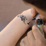 An artist painting custom temporary tattoo on a person