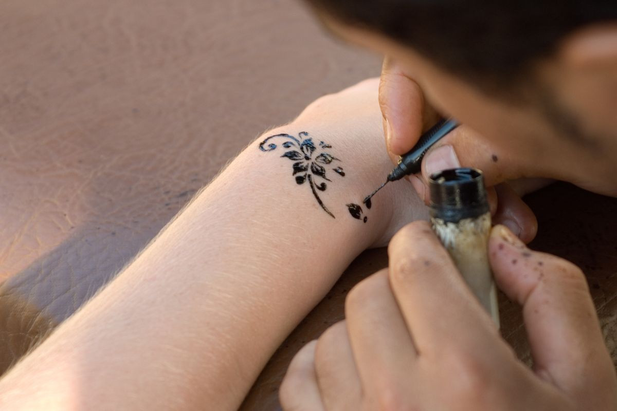 An artist painting custom temporary tattoo on a person