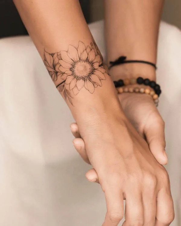Bold black and grey sunflower bracelet tattoo design by @nia.tattooing