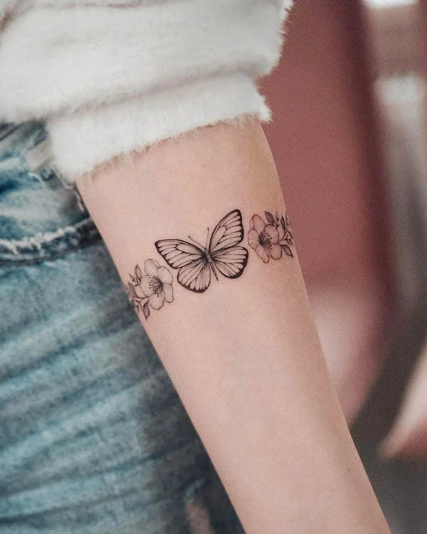 Vibrant butterfly and flowers bracelet tattoo by @bunami.ink_