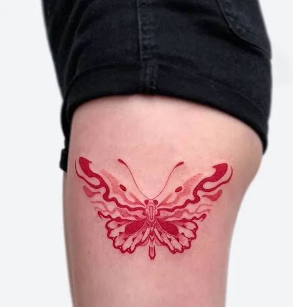 Vibrant red butterfly tattoo on the thigh, by @nxe_xiner, symbolizing passion and transformation