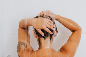 Woman smiling, showing off new arm tattoo, applying lotion