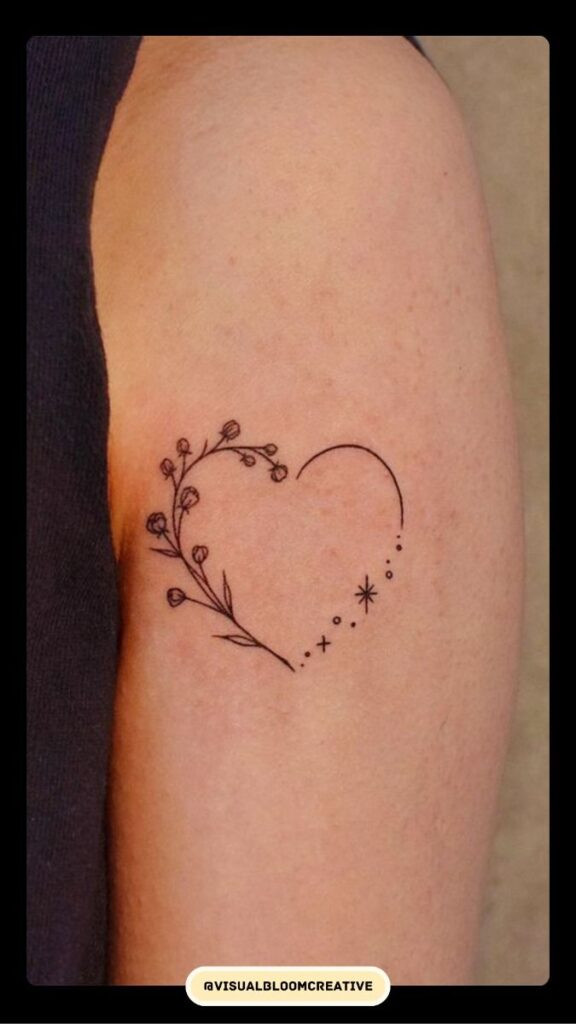 Minimalist heart tattoo with floral and celestial elements on an arm.