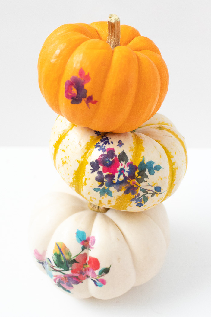 A collection of mini pumpkins decorated with temporary tattoos, displaying various floral designs
