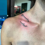 A classic black ink fish hook tattoo on the wrist, symbolizing strength and simplicity