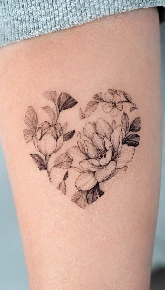 Delicate floral tattoo shaped as a heart, featuring intricate flowers and leaves on a person