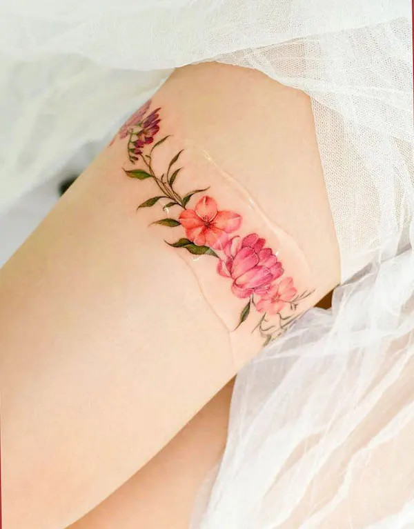 Flower thigh band tattoo with delicate blooms, by @yerae_tt, symbolizing beauty and connection