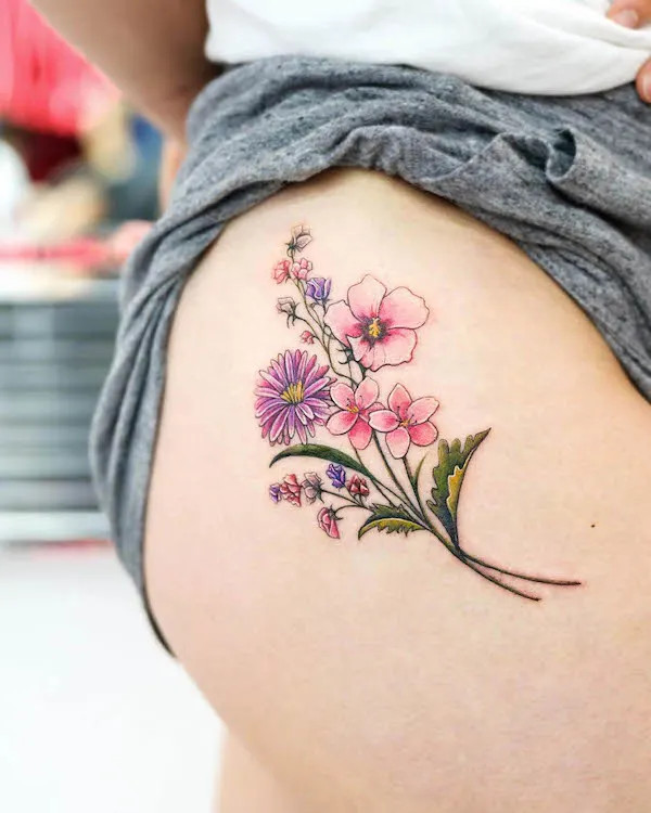 A collection of family birth flowers tattooed on the thigh, by @jooyoung_tt, symbolizing unity and familial bonds