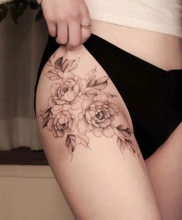 An elegant cluster of black and grey flowers tattooed on the thigh, by @saku.tatt_, showcasing understated beauty and detail