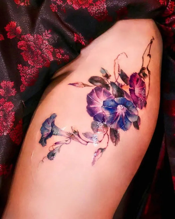 A graceful arrangement of morning glory and vines tattooed on the thigh, by @seolheetattoo, symbolizing new beginnings and growth