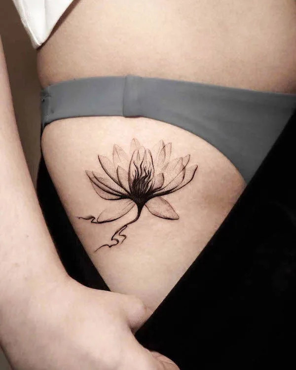 Black and grey lotus flower tattoo on the thigh, by @vimanatattoostudio, symbolizing purity, calmness, and spiritual awakening
