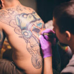 Man having his back tattooed, indicating the location for the tattoo