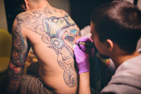 Man having his back tattooed, indicating the location for the tattoo