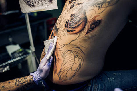Tattoo artist working on a back tattoo
