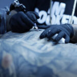 Tattoo artist working on a detailed arm tattoo.
