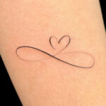 Minimalist infinity heart tattoo on skin, symbolizing eternal love and connection.