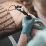 Close-up of a coil tattoo machine in action, highlighting the intricate details of the coils and needles