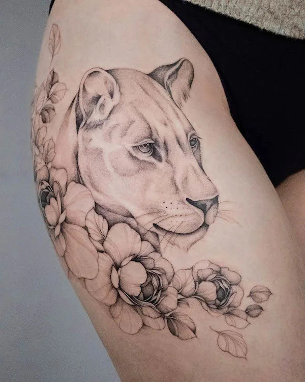 Lion and flower tattoo on the thigh, by @tasiatattoos, blending strength with natural beauty