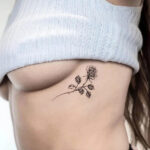 Minimalist flower rib tattoo by @jk.tattoo