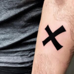 One Piece X tattoo on a woman’s forearm