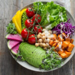 A person enjoying a healthy and balanced meal before their tattoo appointment, filled with colorful vegetables and lean protein.
