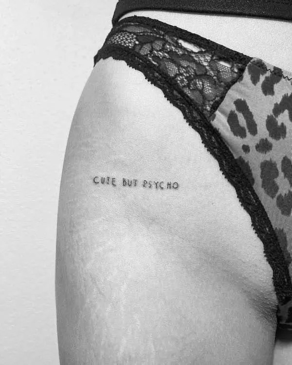 Statement quote tattoo on the upper thigh, by @line.art_.tattoo, conveying a powerful personal message