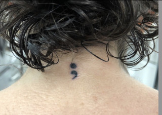 Semicolon tattoo on wrist signifying mental health awareness and resilience