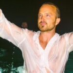 Aaron Paul showing his "No Half Measures" tattoo, a tribute to Breaking Bad, symbolizing commitment and dedication.